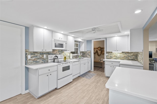 7122 11th Ave W, Bradenton, FL 34209 - kitchen with ceiling fan, light countertops, a tray ceiling, white appliances, and a sink