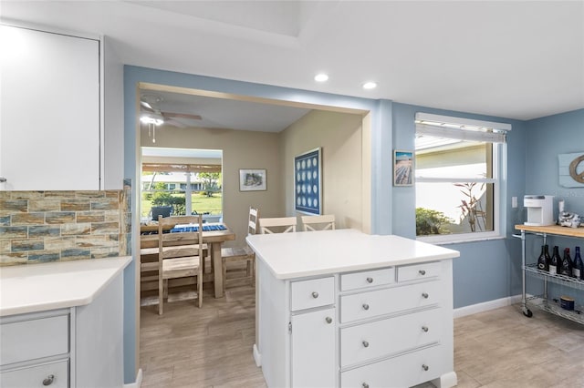 7122 11th Ave W, Bradenton, FL 34209 - kitchen with baseboards, light countertops, light wood-style floors, white cabinets, and a ceiling fan