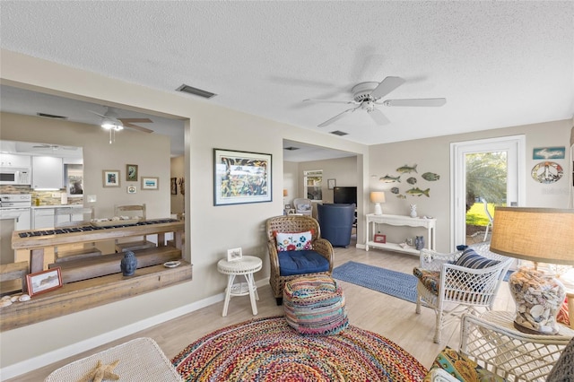 7122 11th Ave W, Bradenton, FL 34209 - living area featuring visible vents, baseboards, light wood-type flooring, a textured ceiling, and a ceiling fan