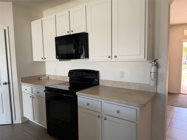 kitchen with arched walkways, white cabinetry, black appliances, and dark tile patterned flooring