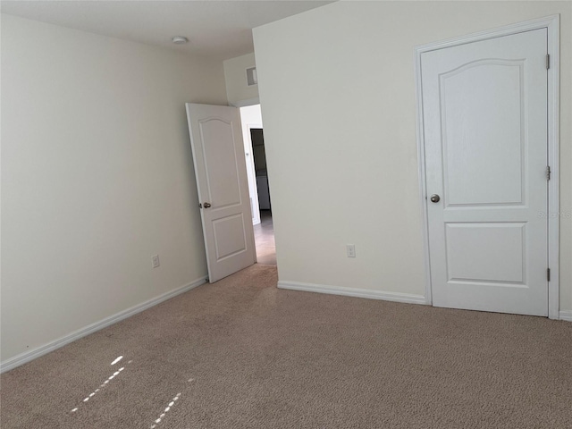 carpeted spare room featuring visible vents and baseboards