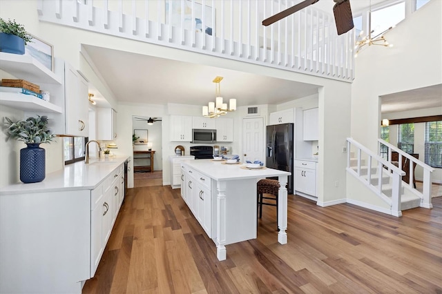 4406 17th St W, Palmetto, FL 34221 - kitchen with stainless steel microwave, a chandelier, range, a ceiling fan, and black refrigerator with ice dispenser