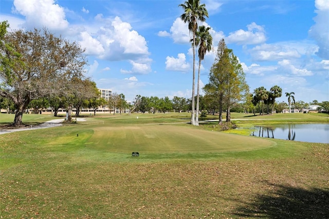 surrounding community with golf course view, a lawn, and a water view