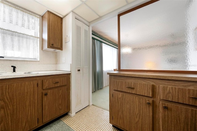kitchen featuring brown cabinetry, light countertops, and a sink