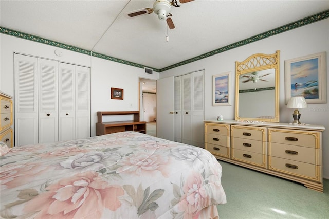 carpeted bedroom featuring multiple closets and a ceiling fan