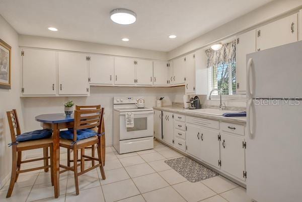 4560 Brooksdale Dr, Sarasota, FL 34232 - kitchen with white appliances, light countertops, a sink, and white cabinets