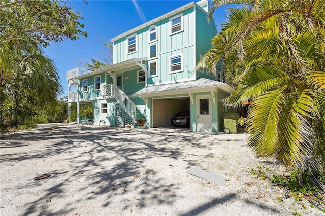 111 Faubel St, Sarasota, FL 34242 - rear view of property featuring metal roof, gravel driveway, stairs, board and batten siding, and a carport