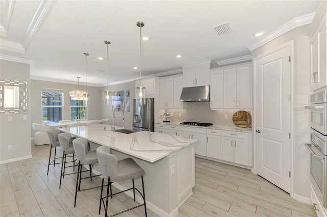 kitchen with crown molding, cooktop, a sink, stainless steel fridge with ice dispenser, and under cabinet range hood