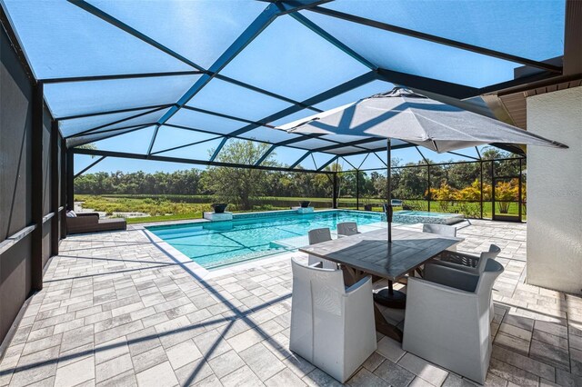 view of pool featuring a lanai, a pool with connected hot tub, and a patio
