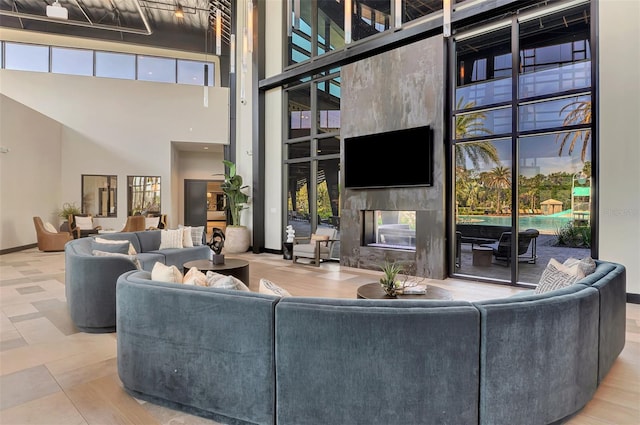 living area with a high end fireplace, baseboards, and a towering ceiling
