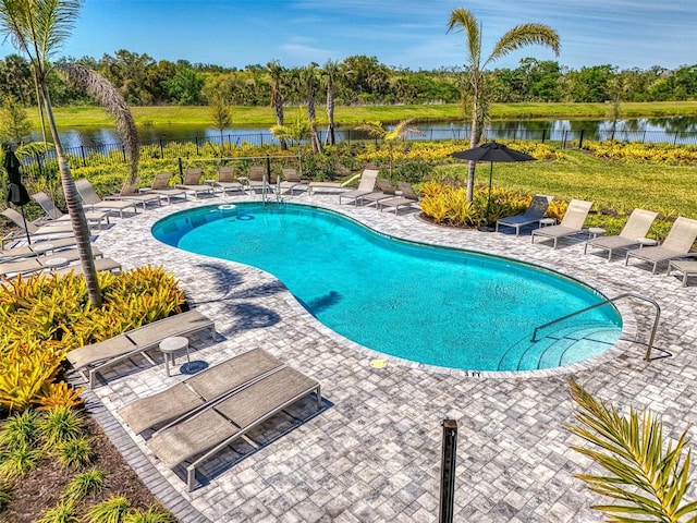 pool with fence, a water view, and a patio