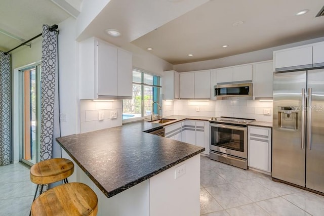 kitchen with backsplash, a sink, stainless steel appliances, and a peninsula