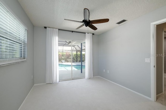 spare room featuring baseboards, carpet flooring, ceiling fan, and visible vents