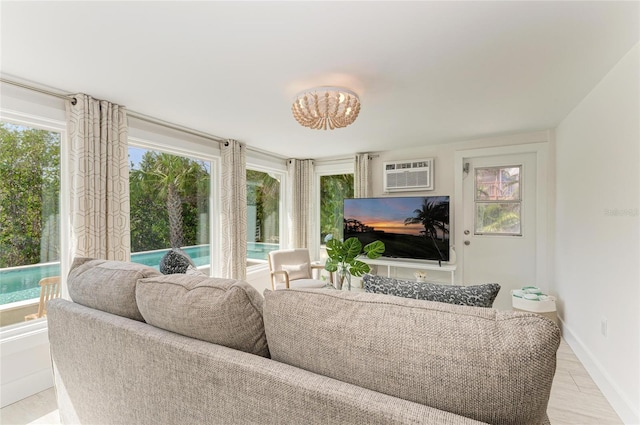 living area featuring a wealth of natural light, baseboards, and an AC wall unit