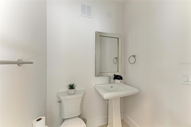 half bathroom featuring visible vents, toilet, and baseboards