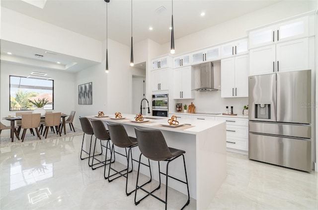 1815 SW 15th Pl, Cape Coral, FL 33991 - kitchen featuring appliances with stainless steel finishes, wall chimney exhaust hood, an island with sink, a breakfast bar area, and light countertops