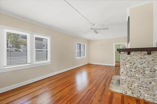 unfurnished living room with a healthy amount of sunlight, wood finished floors, baseboards, and a ceiling fan
