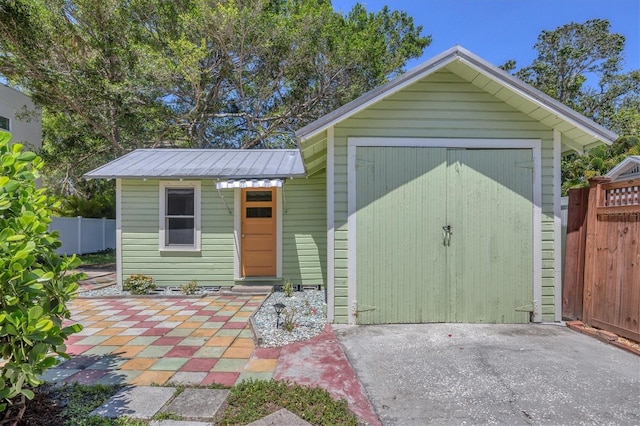 view of outbuilding with driveway, an outdoor structure, and fence