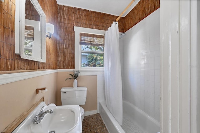 full bathroom featuring toilet, shower / bath combo with shower curtain, a sink, and baseboards