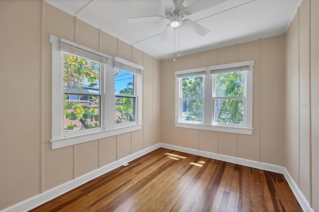 unfurnished room featuring a decorative wall, hardwood / wood-style floors, and a ceiling fan