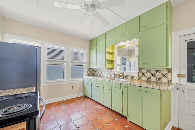 kitchen with electric range oven, a sink, ceiling fan, freestanding refrigerator, and backsplash