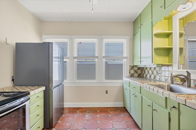 kitchen with tile counters, a sink, open shelves, and green cabinetry