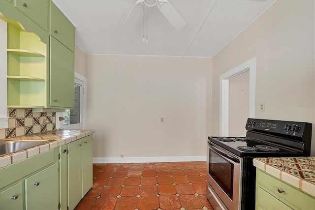 kitchen featuring green cabinets, open shelves, tile counters, and stainless steel range with electric stovetop