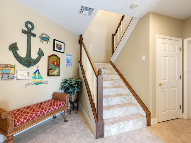 stairway with baseboards, visible vents, and tile patterned floors