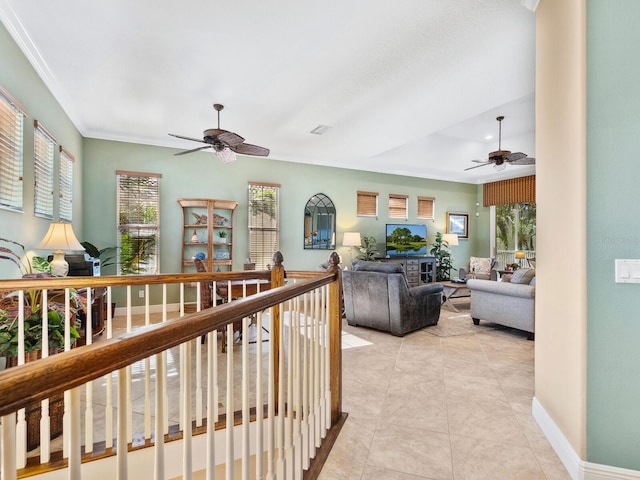 living area with a ceiling fan, light tile patterned flooring, ornamental molding, and baseboards