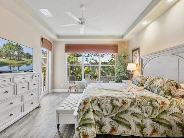 bedroom featuring visible vents, baseboards, access to outside, a raised ceiling, and light wood-type flooring