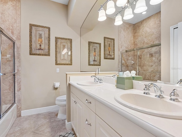 bathroom with baseboards, double vanity, a sink, and toilet