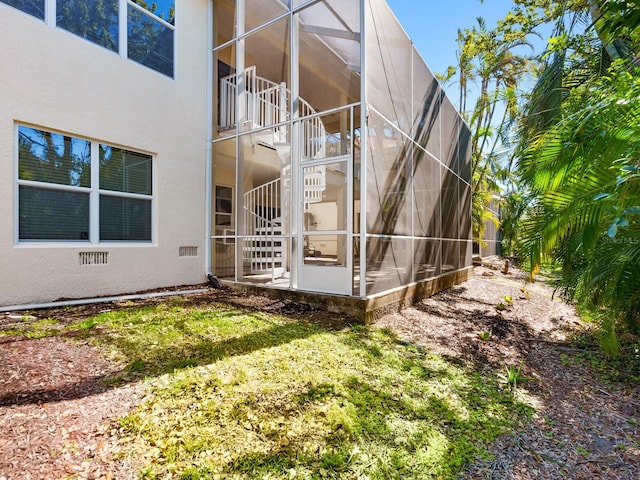 view of property exterior with glass enclosure, stucco siding, and a patio area