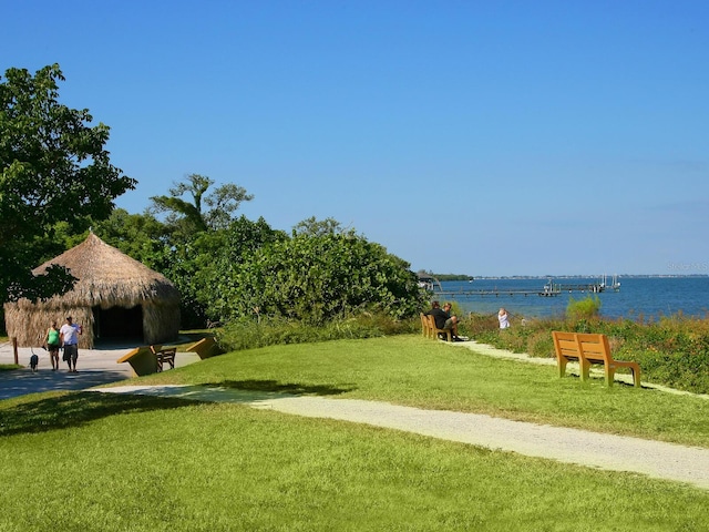 surrounding community with a water view and a yard