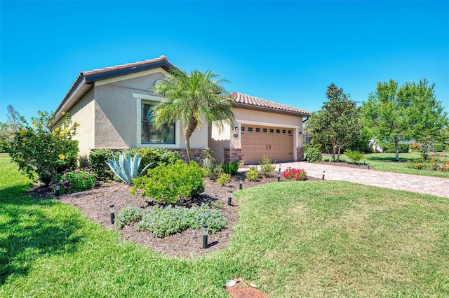 view of front facade with driveway, stucco siding, an attached garage, a front lawn, and a tiled roof