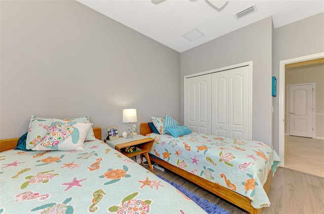 bedroom featuring light wood finished floors, visible vents, a closet, and a ceiling fan