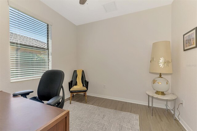office space with baseboards, visible vents, light wood-style floors, and a ceiling fan
