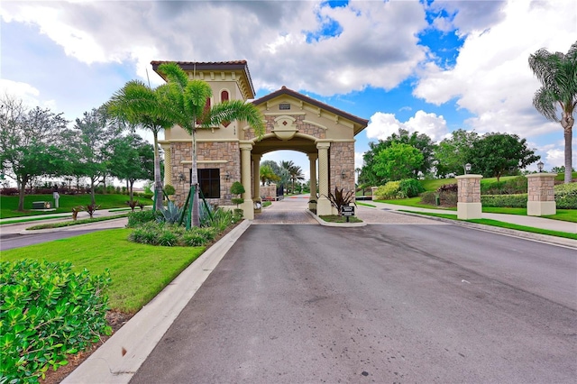 view of road featuring sidewalks, a gated entry, and curbs