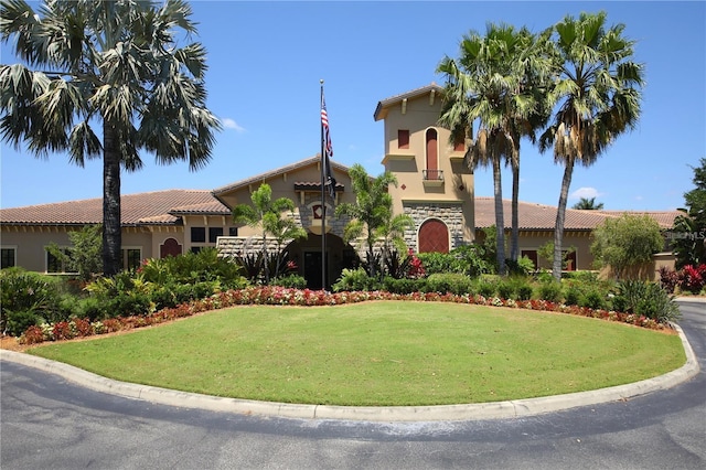 view of front of property with stucco siding, a tile roof, and a front yard