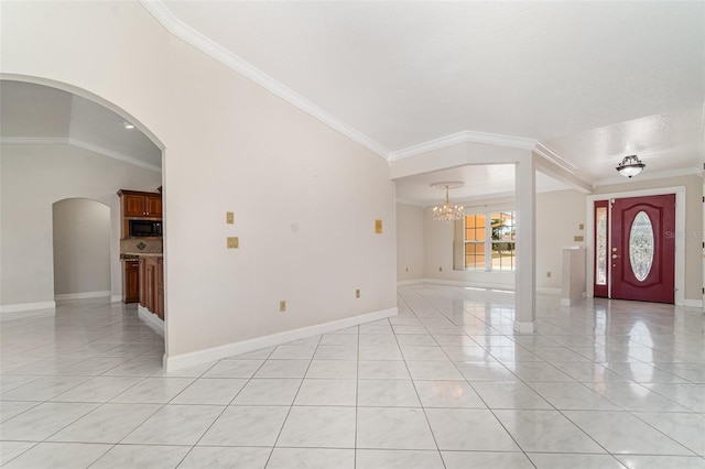 entryway with light tile patterned floors, baseboards, arched walkways, ornamental molding, and a chandelier