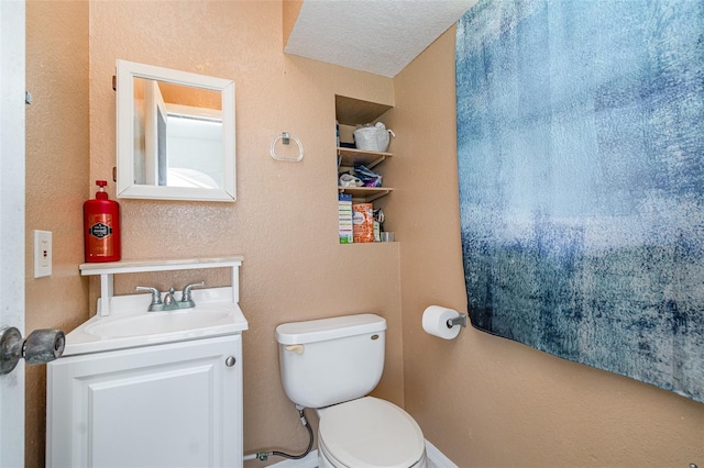 bathroom featuring toilet, vanity, and a textured wall