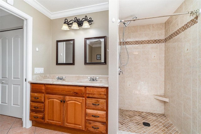 bathroom featuring double vanity, a tile shower, a sink, crown molding, and tile patterned floors