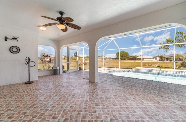 view of patio / terrace with an outdoor pool, glass enclosure, and a ceiling fan