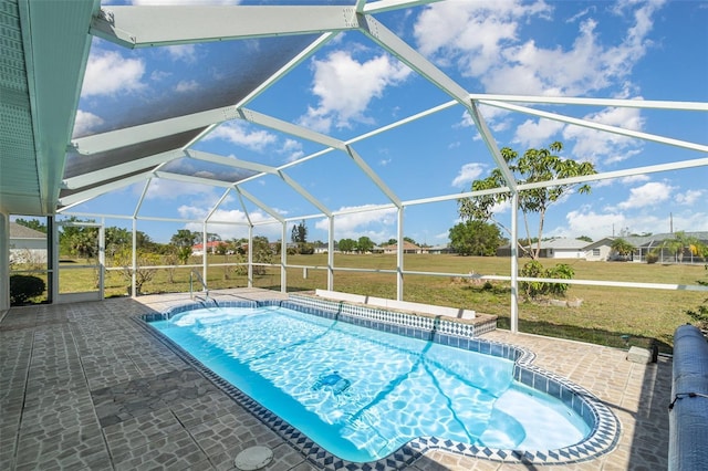 outdoor pool featuring glass enclosure, a patio, and a yard