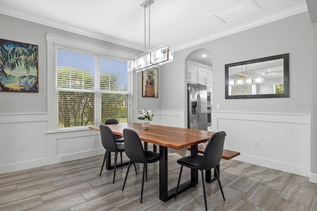 5954 Anise Dr, Sarasota, FL 34238 - dining space featuring crown molding, a wainscoted wall, a decorative wall, arched walkways, and a chandelier
