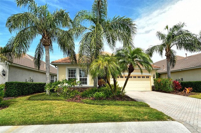 7137 Orchid Island Pl, Bradenton, FL 34202 - view of front of house with stucco siding, driveway, a front lawn, a tile roof, and a garage