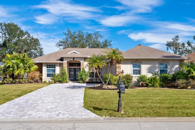 ranch-style house with french doors, stucco siding, a front lawn, and decorative driveway