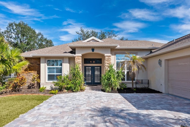 2439 Sonoma Dr W, Nokomis, FL 34275 - view of front of property featuring french doors, stucco siding, stone siding, decorative driveway, and a garage