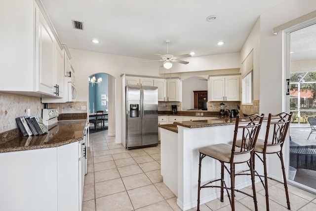 2439 Sonoma Dr W, Nokomis, FL 34275 - kitchen with white appliances, arched walkways, a kitchen breakfast bar, backsplash, and white cabinets