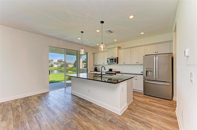 10614 Morning Marsh Ln, Parrish, FL 34219 - kitchen with stainless steel appliances, dark countertops, light wood-style flooring, an island with sink, and recessed lighting