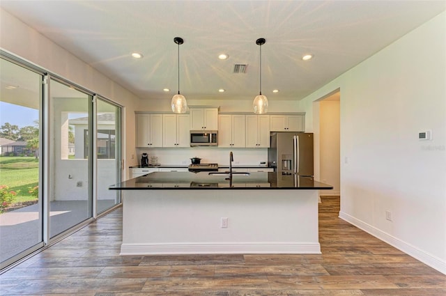 10614 Morning Marsh Ln, Parrish, FL 34219 - kitchen with appliances with stainless steel finishes, dark countertops, a center island with sink, recessed lighting, and dark wood-style floors